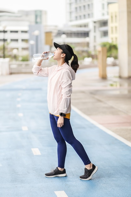 Une jeune et active femme asiatique qui boit la bouteille d&#39;eau