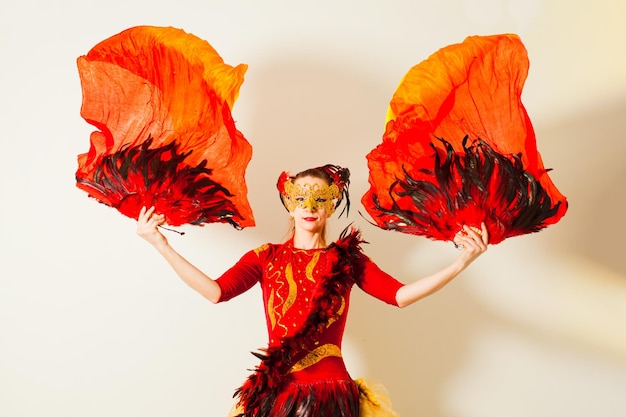 Jeune actrice en costume vif de caractère extraordinaire Femme dansant avec des éventails de plumes rouges et de longs voiles dans ses mains Portrait en studio sur fond blanc