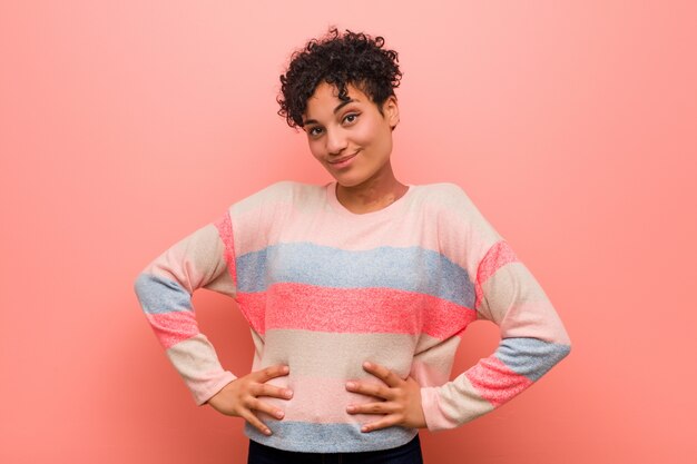 Photo jeune adolescent afro-américaine mixte confiant femme gardant les mains sur les hanches.