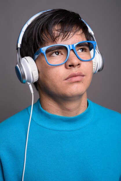 Jeune adolescent asiatique écoutant de la musique contre backgrou gris