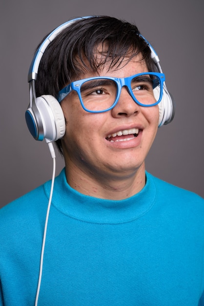 Jeune adolescent asiatique écoutant de la musique contre backgrou gris