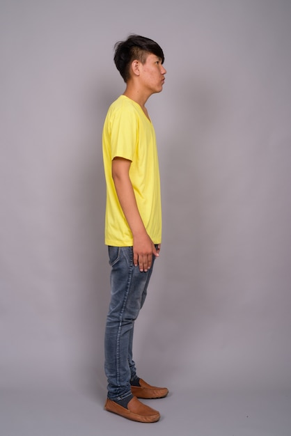 Jeune adolescent asiatique portant une chemise jaune sur fond gris