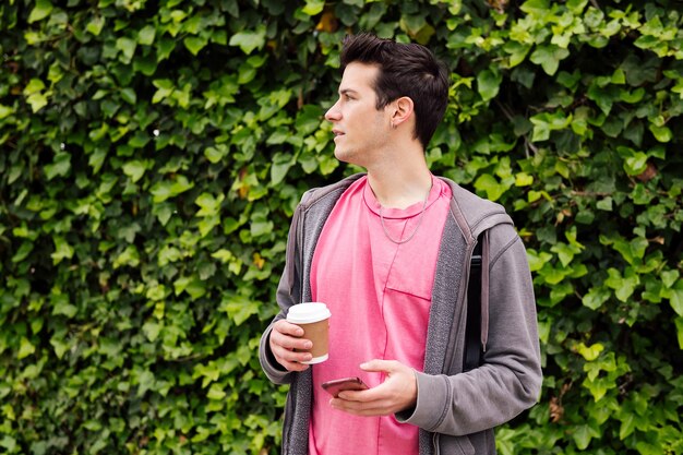 Jeune adolescent avec un café à l'aide d'un téléphone intelligent