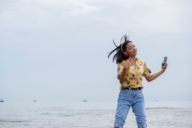 Jeune adolescent dansant et écoutant de la musique à la belle plage