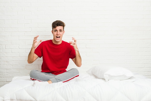 Jeune adolescent étudiant homme sur le lit criant de rage.