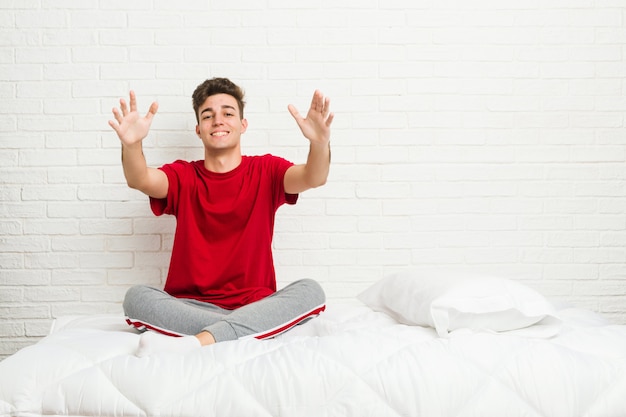 Jeune adolescent étudiant homme sur le lit se sent confiant donnant un câlin
