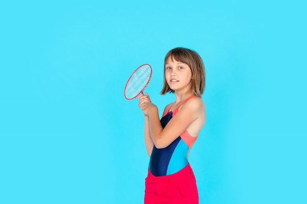 Jeune adolescent fille sautant et jouant au badminton sur mur bleu