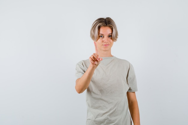 Jeune adolescent montrant un geste de la minute en t-shirt et l'air confiant. vue de face.