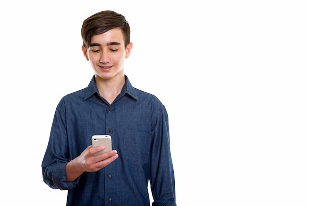 Jeune adolescent persan heureux souriant tout en utilisant un téléphone mobile