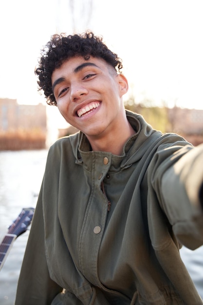 Photo jeune adolescent prenant un selfie avec un smartphone dans un parc de la ville