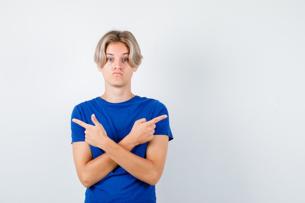 Jeune adolescent en t-shirt bleu pointant vers la droite et la gauche et l'air confus, vue de face.