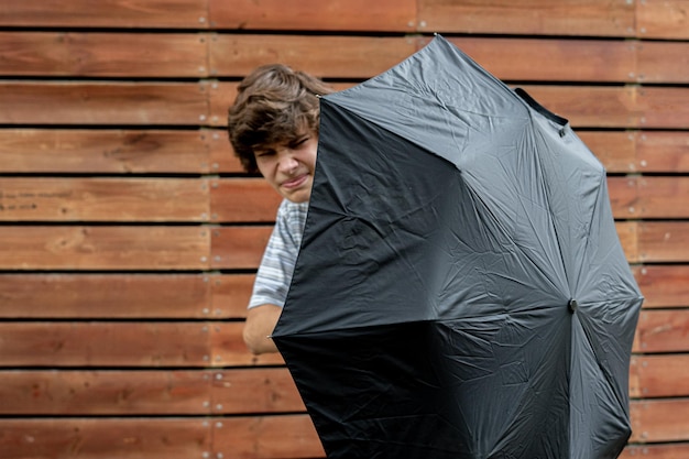 Jeune adolescent tenant un parapluie se protégeant du problème