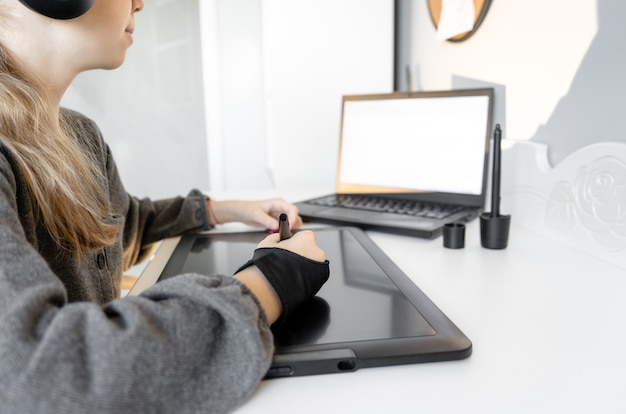 Jeune adolescente à l'aide d'une tablette graphique numérique et d'un stylo à dessin pour une nouvelle image. Leçon de dessin pédagogique en ligne.