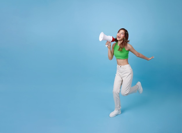 Photo une jeune adolescente asiatique court et tient un mégaphone à la main pour annoncer une remise.