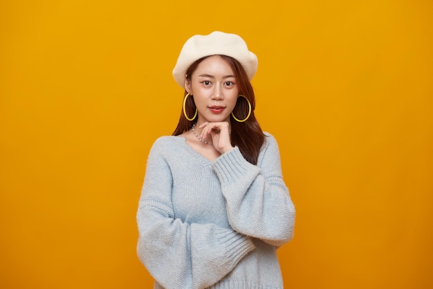 Une jeune adolescente asiatique heureuse et souriante, joyeuse et isolée sur un fond jaune.