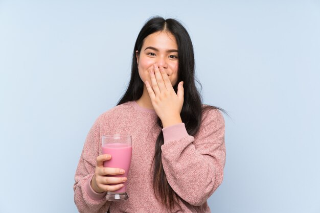 Jeune adolescente asiatique avec un milkshake à la fraise avec une expression faciale surprise