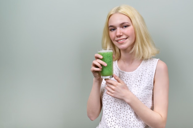 Jeune adolescente avec boisson smoothie aux légumes verts, régime végétalien sain, espace de copie. Santé, alimentation, végétarienne, femme sur fond vert pastel