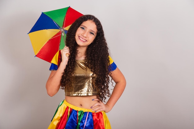 Jeune adolescente brésilienne avec carnaval de vêtements frevo avec parapluie et mains sur la taille