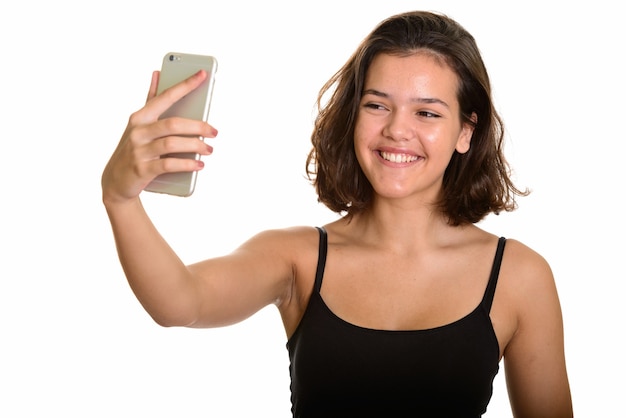 Jeune adolescente caucasienne heureuse souriant et prenant selfie avec téléphone mobile