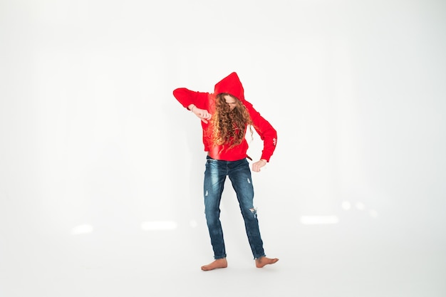 Jeune adolescente danse en pleine croissance sur fond blanc en studio dans les rayons du soleil