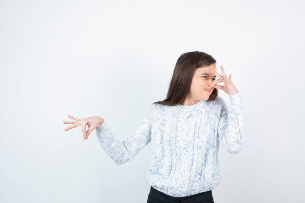 Jeune adolescente debout et couvrant son nez avec dégoût.