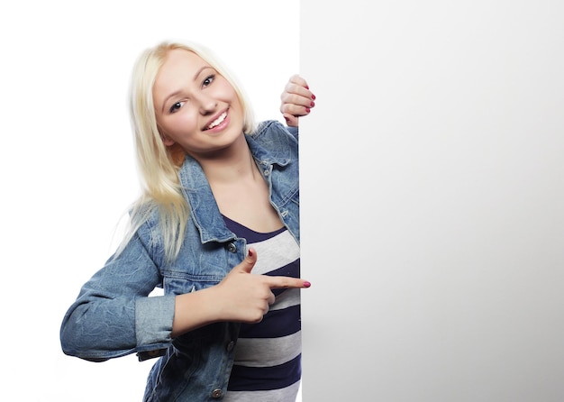 Jeune adolescente heureuse pointant sur tableau blanc fond blanc