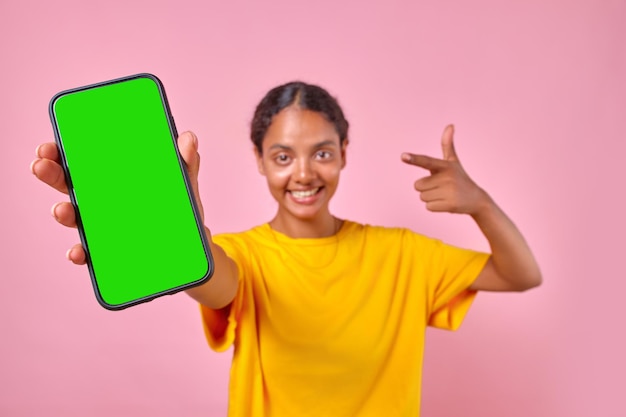 Une jeune adolescente indienne joyeuse montre des supports de téléphone portable en studio