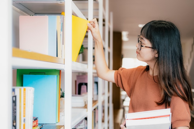 Jeune adolescente rendant l'ordre sur les étagères de la librairie.