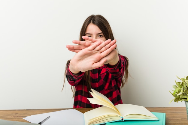 Jeune adolescente retournant à sa routine faire ses devoirs faisant un geste de déni