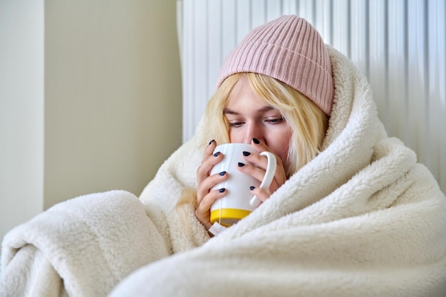 Jeune adolescente se réchauffant avec du thé chaud de radiateur de chauffage de couverture