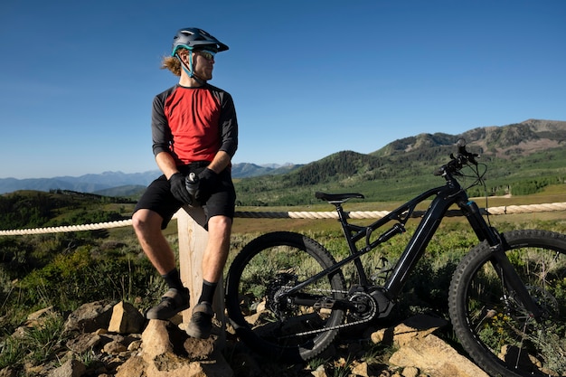 Photo jeune adulte à l'aide de vélo électrique à la campagne