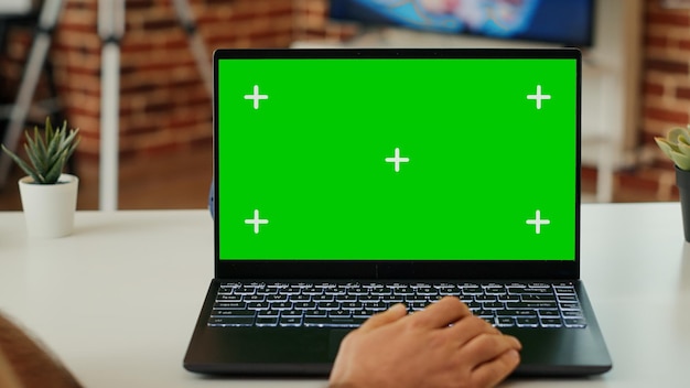 Jeune adulte analysant l'écran vert sur un ordinateur personnel, regardant un modèle de maquette isolé et travaillant avec une clé chroma. Utilisation d'un espace de copie vierge sur un ordinateur portable à la maison. Fermer.