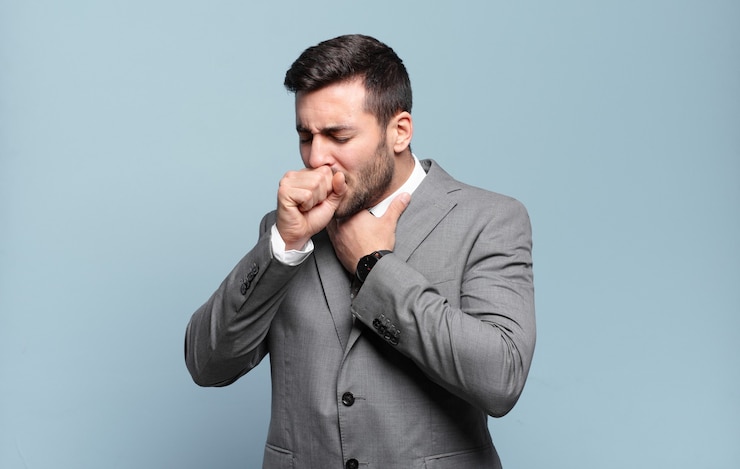 Photo jeune adulte bel homme d'affaires se sentant malade avec un mal de gorge et des symptômes de grippe, toussant avec la bouche couverte