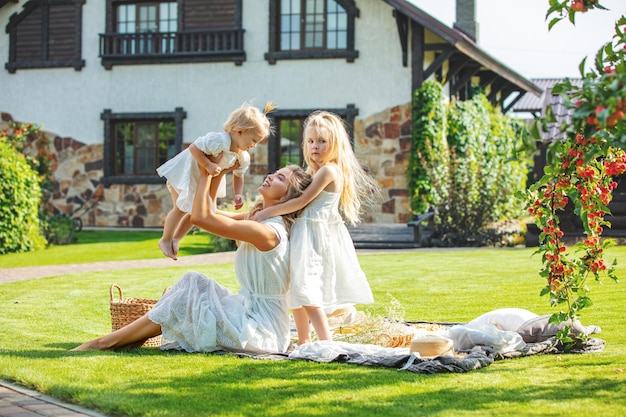 Photo jeune adulte belle femme vêtue d'une robe avec des enfants en pique-nique dans le jardin à la maison