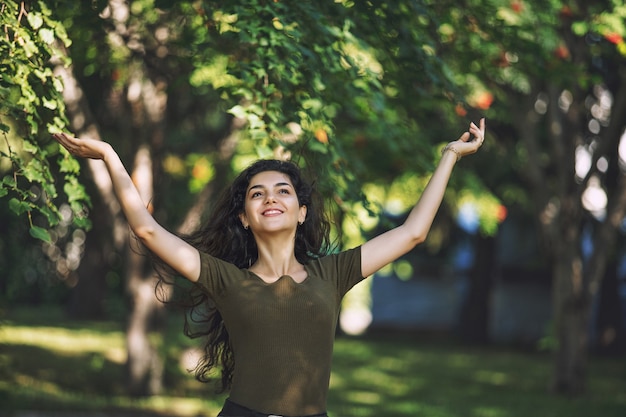 Jeune adulte belle fille brune en vêtements décontractés heureux pour une promenade dans le parc