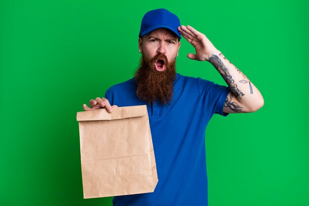 Jeune adulte cheveux roux barbu livreur cool avec un sac en papier