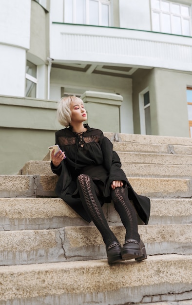 Jeune adulte femme asiatique blonde en regardant son téléphone dans les escaliers du bâtiment, selective focus