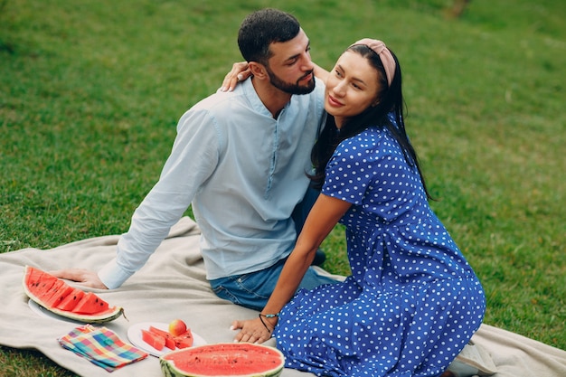 Jeune adulte femme et homme couple pique-nique au pré d'herbe verte dans le parc avec des fruits et un panier.