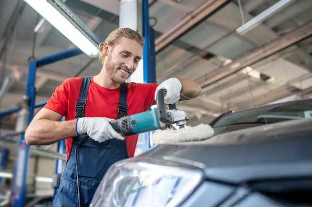 Jeune adulte homme confiant en uniforme de travail travaillant sur des voitures