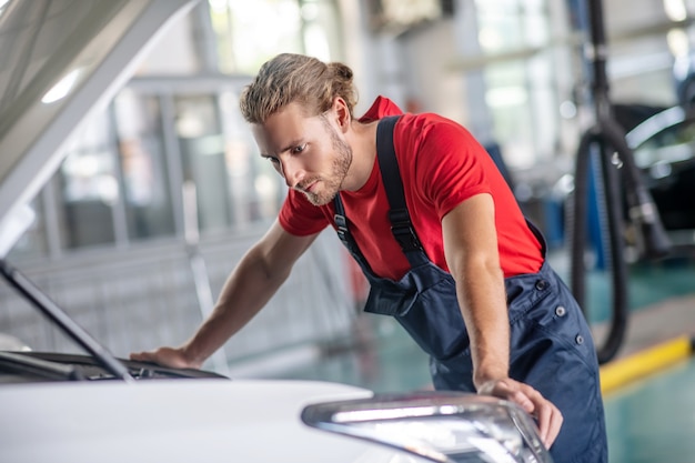 Jeune adulte homme confiant en uniforme de travail travaillant sur des voitures