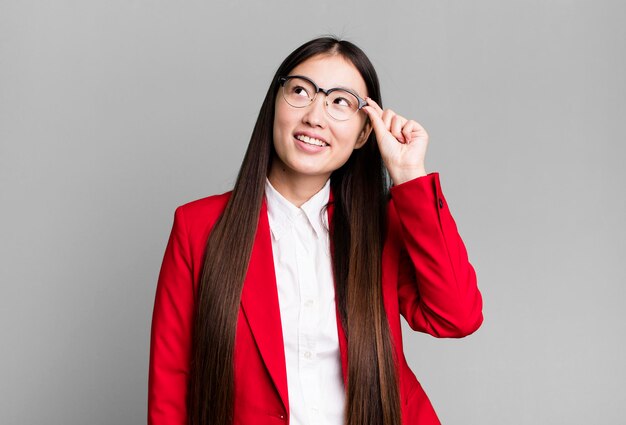 Jeune adulte jolie femme d'affaires asiatique portant un blazer rouge et des lunettes