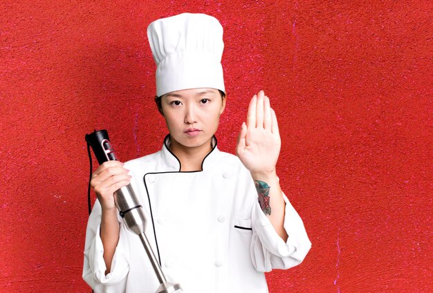 Photo jeune adulte jolie femme asiatique chef de restaurant avec un mélangeur à main