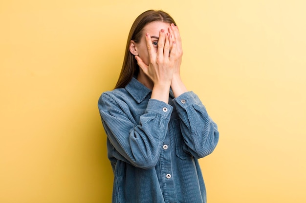 Jeune adulte jolie femme isolée contre le mur jaune
