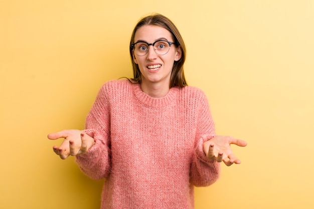 Jeune adulte jolie femme isolée contre le mur jaune