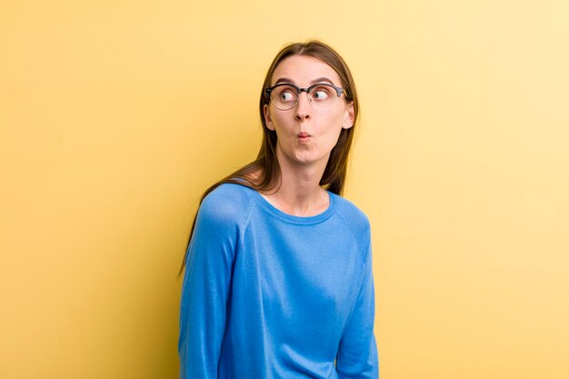 Jeune adulte jolie femme isolée contre le mur jaune