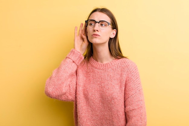 Jeune adulte jolie femme isolée contre le mur jaune