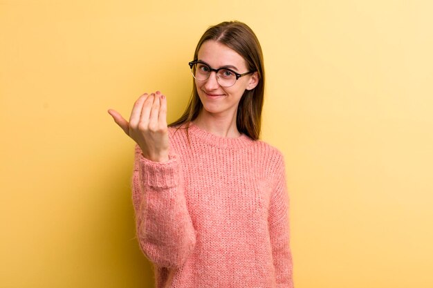 Jeune adulte jolie femme isolée contre le mur jaune