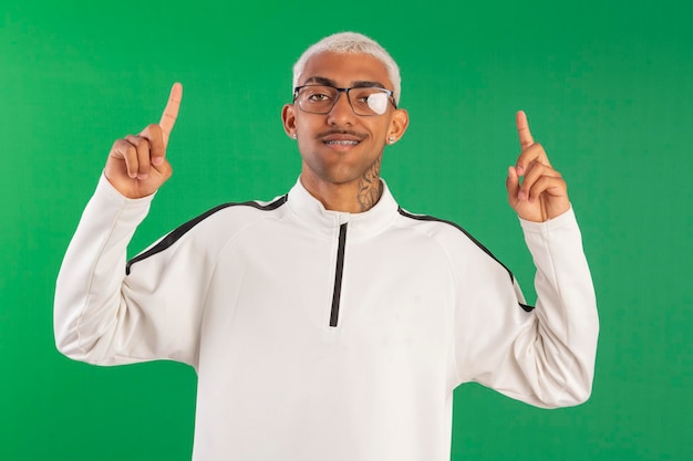 Jeune adulte de la périphérie avec des cheveux 'blonde pivete' en studio photo avec un fond vert