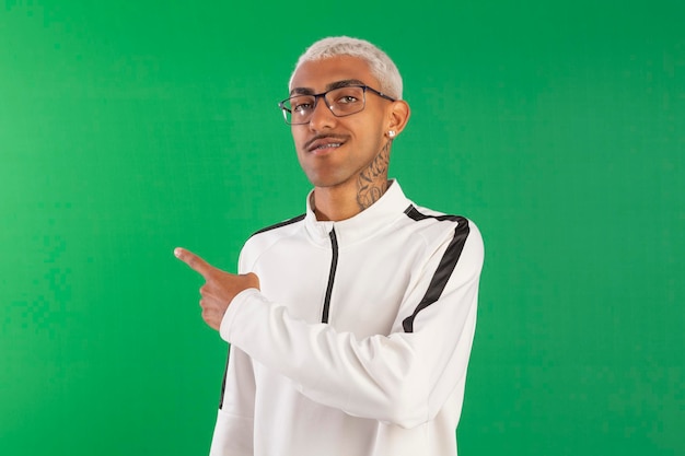 Jeune adulte de la périphérie avec des cheveux 'blonde pivete' en studio photo avec un fond vert