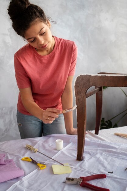 Jeune adulte réparant une vieille chaise